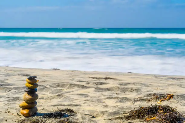 Stacked stones/ pebbles naturally balanced on a sunny summer day by the beach. Rock Zen stack balancing. Meditation symbol of peace and harmony.