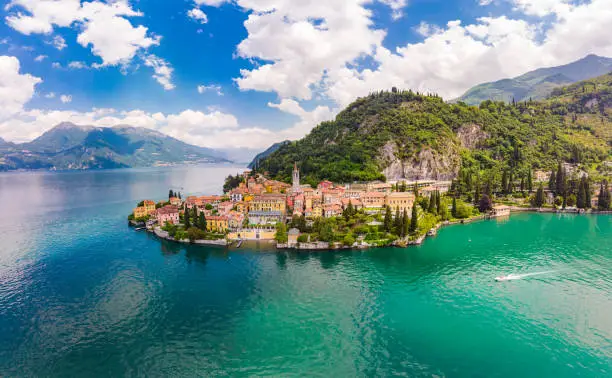 Photo of Beautifull aerial panoramic view from the drone to the Varenna - famous old Italy town on bank of Como lake. High top view to Water landscape with green hills, mountains and city in sunny summer day.