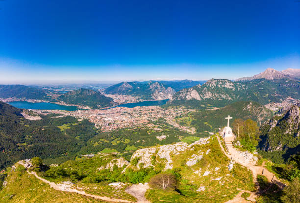 Beautiful panoramic sunrise landscape at town Lecco, lake Como in sunny summer day. Stunning airial view to cross on top of mountain from drone near viewpoint Piani, Pizzo, d'Erna, alps, italy, Europe hermoso paisaje panorámico del amanecer en la ciudad de lecco, lago como en el día soleado del verano. impresionante vista aérea para cruzar en la cima de la montaña desde drone cerca del mirador piani pizzo d'erna, alpes, italia, europa