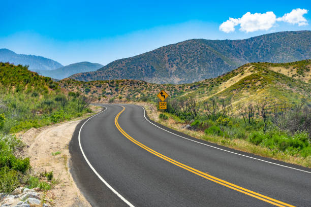 istock Curved mountain road with 30 MPH caution road sign 1166668376