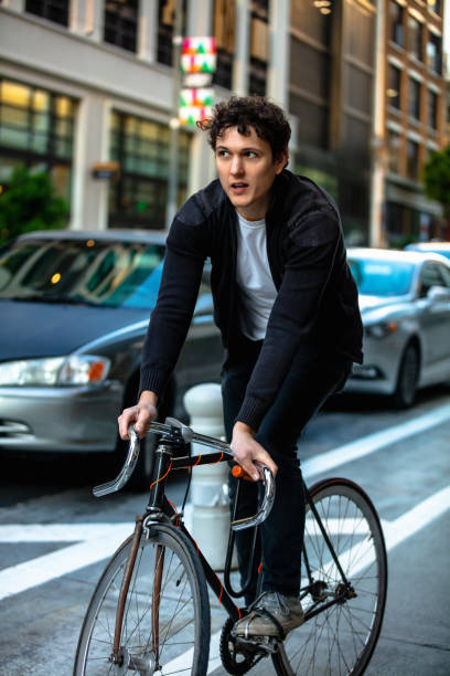 istock Quizzical Young Man Riding in Protected Bike Lane 1166670978