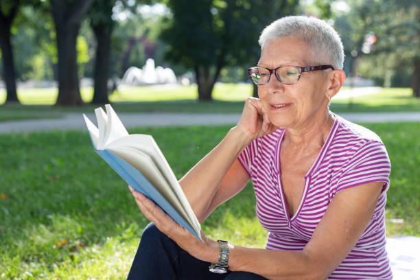 istock Senior woman reading a book at park 1166677977