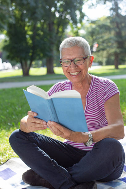 istock Senior woman reading a book at park 1166678024