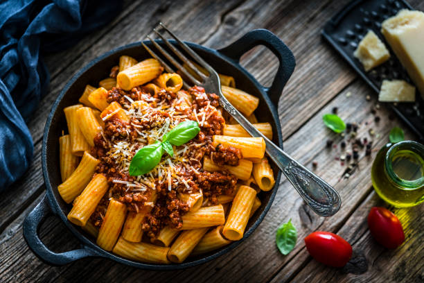 istock Rigatoni pasta with Bolognese sauce shot on rustic wooden table 1166678092