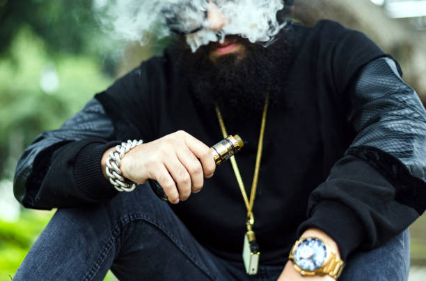 istock man with a beard smokes an electronic cigarette sit on a bench 1166680714