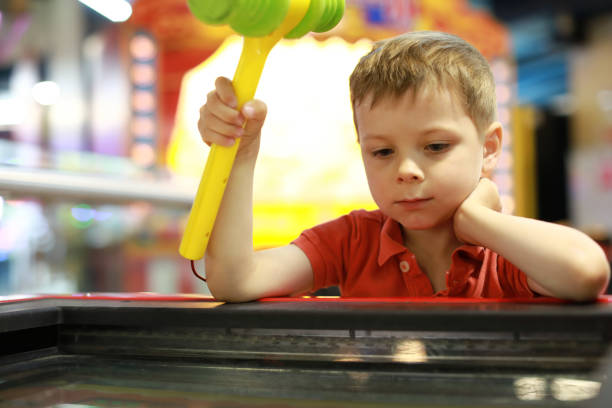 Happy toddler joyfully playing on a vibrant red slide in an indoor playground, surrounded by colorful play areas and laughter