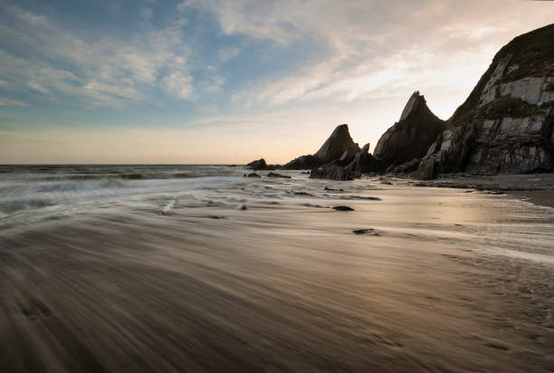 istock Stunning sunset landscape image of Westcombe Beach in Devon England with jagged rocks on beach and stunning cloud formations 1166682728