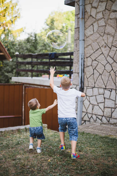 istock Two cute kids blowing bubbles in the front of yard 1166682735
