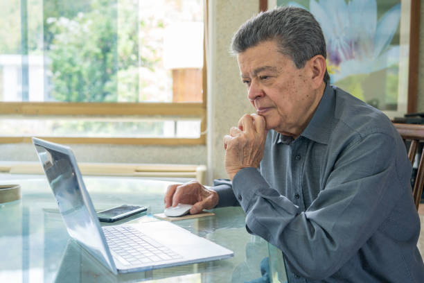 Hispanic senior man working at home office with laptop computer. Home office concepts stock photo
