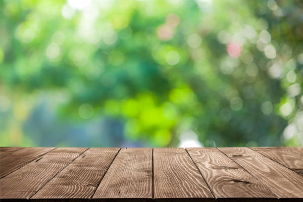 Backgrounds: Empty wooden table with defocused green lush foliage at background Empty rustic wooden table with defocused green lush foliage at background. Ideal for product display on top of the table. Predominant color are green and brown. DSRL studio photo taken with Canon EOS 5D Mk II and Canon EF 100mm f/2.8L Macro IS USM. high section photos stock pictures, royalty-free photos & images