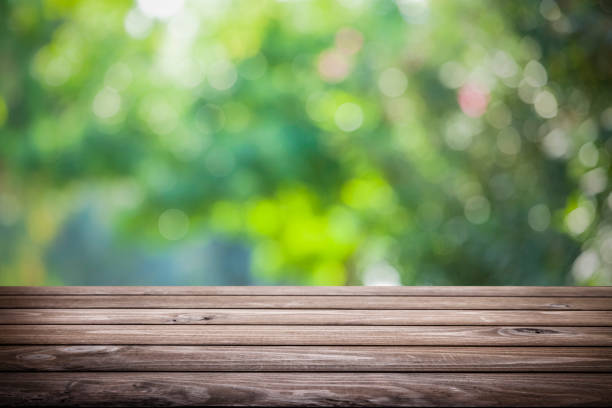 istock Backgrounds: Empty wooden table with defocused green lush foliage at background 1166687465