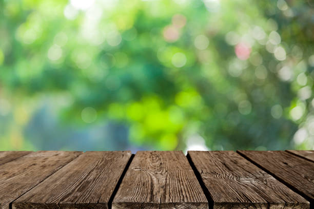 istock Backgrounds: Empty wooden table with defocused green lush foliage at background 1166687466