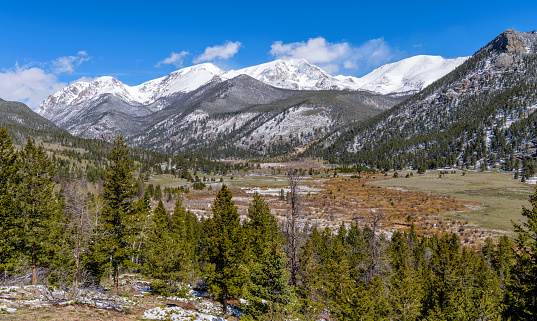 A panoramic view of Rocky Mountain National Park on a sunny morning after a Spring snowstorm, with snow-capped Mummy Range towering in background, Colorado, USA.