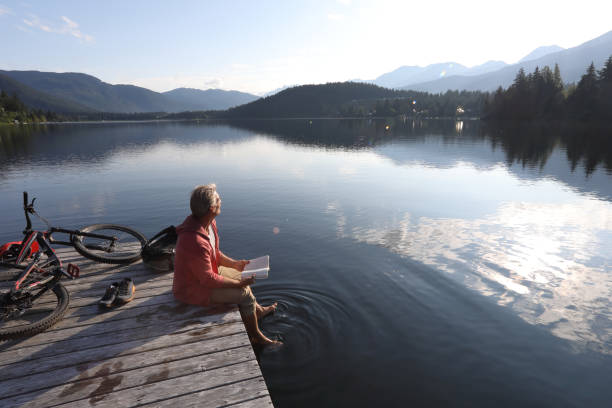 He looks off to distant scene, while dabbling feet in clear lake water