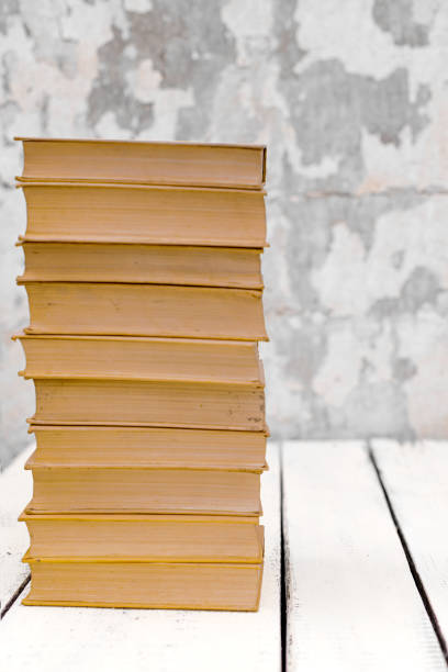 istock Stack of old ancient shabby books on a white wooden background. 1166696121