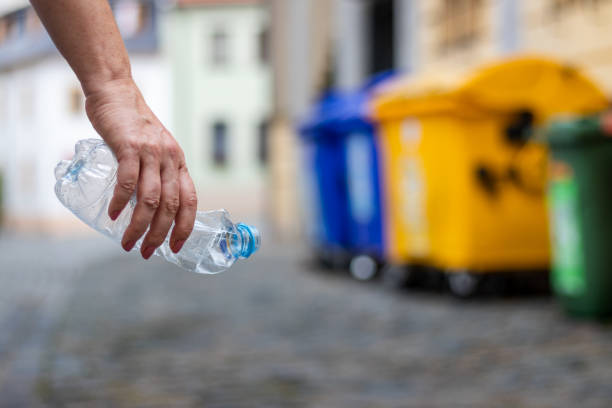 istock Evironmental issues. Hand holding plastic bottle at city street. 1166696319