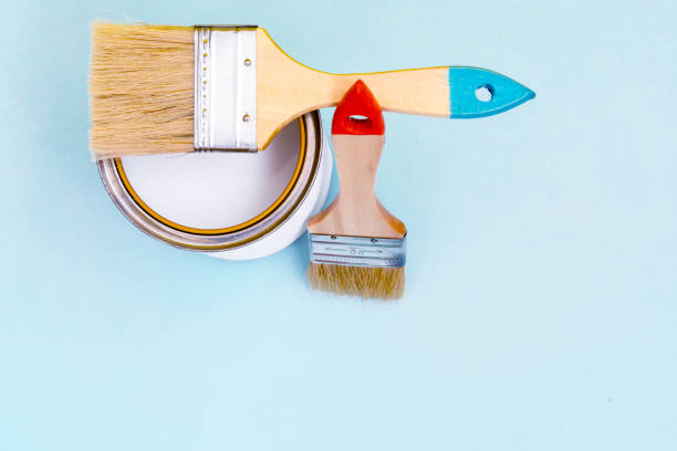 istock Brush with wooden handle on open cans on blue pastel background. Renovation concept. Place for text. 1166698775