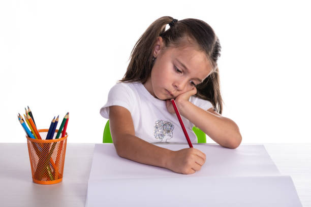 selective focus of upset kid looking at camera near papers with drawing