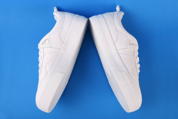 istock A pair of white sneakers on the blue background 1166702278