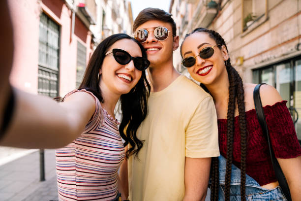 Group of young friends using mobile phone Group of young friends taking selfie in the street. Addiction concept selfie madrid photos stock pictures, royalty-free photos & images