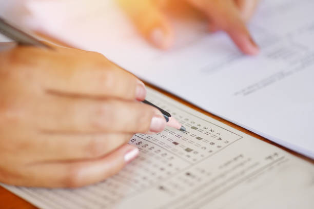 istock take the exam final high school hand student holding pencil writing on paper answer sheet - education college in class taking notes sitting learning writing selected choice in examination room 1166709635