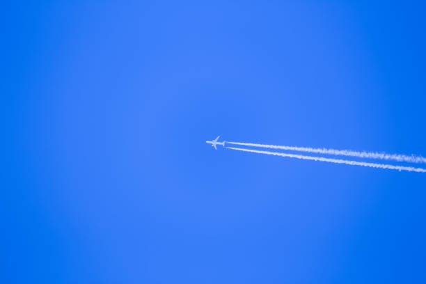 istock White airplane across the blue sky with smoke 1166713505