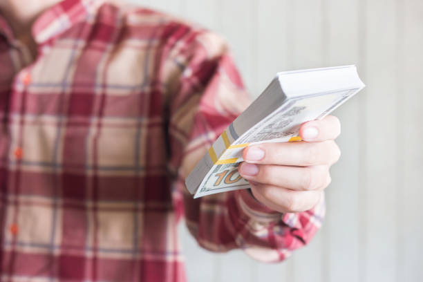 les jeunes hommes portent la chemise rouge de gingham retenant des billets d'un dollar - tyle photos et images de collection