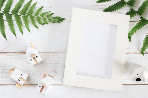 istock Mock up, Blank White Picture frame with Fern leaf and Miniature white house model 1166713562