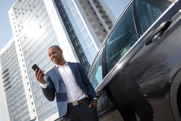 istock Young businessman standing near car browsing smartphone joyful bottom view 1166715840