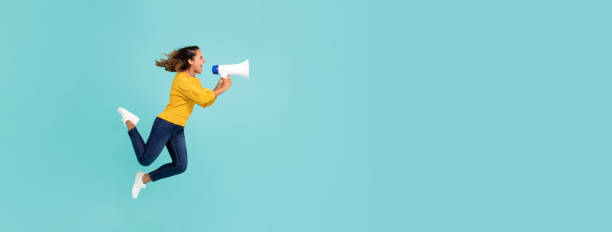 Girl with megaphone jumping and shouting Young African American girl with megaphone jumping and shouting on light blue banner background with copy space persuasion photos stock pictures, royalty-free photos & images