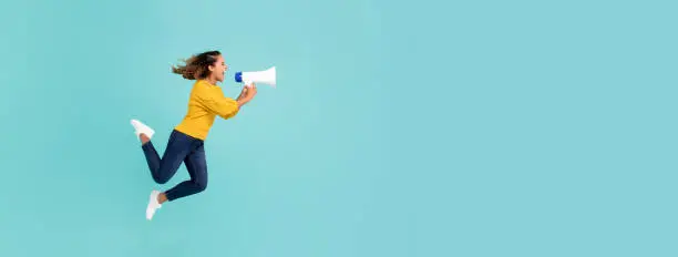 Photo of Girl with megaphone jumping and shouting