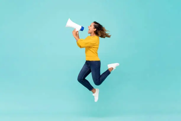 Photo of Girl with megaphone jumping and shouting