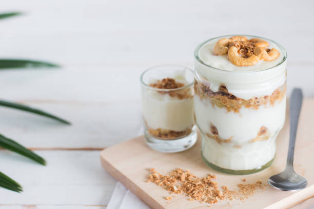 pasto sano a base di muesli in vetro, yogurt e cornflakes decorare il cibo con noce di anacardi - tyle foto e immagini stock