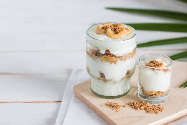 pasto sano a base di muesli in vetro, yogurt e cornflakes decorare il cibo con noce di anacardi - tyle foto e immagini stock