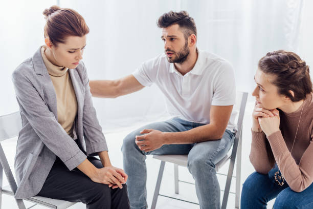 istock man consoling sad woman during group therapy session 1166724126