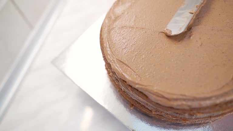 Close up of woman icing a cake with chocolate cream