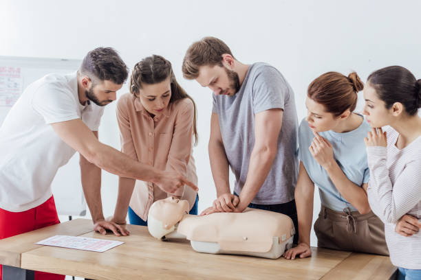 group of people with instructor performing cpr on dummy during first aid training group of people with instructor performing cpr on dummy during first aid training first aid class stock pictures, royalty-free photos & images