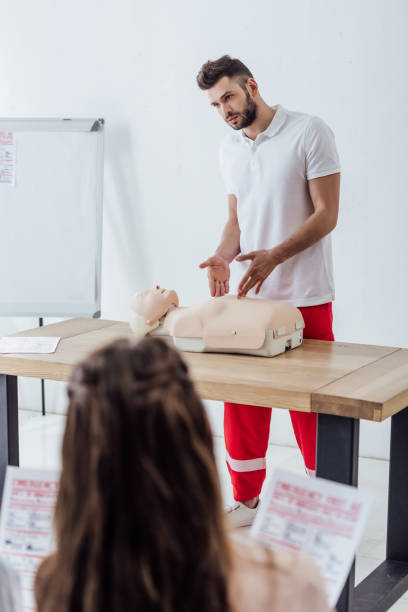 handsome instructor gesturing with hands during first aid training class handsome instructor gesturing with hands during first aid training class first aid class stock pictures, royalty-free photos & images