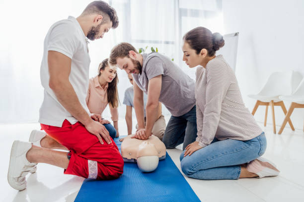 group of people looking at man performing cpr on dummy during first aid training