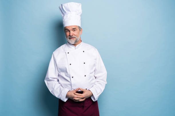 istock Attractive smiling cheerful chef isolated on blue. 1166727866