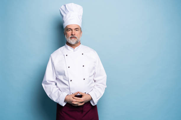 istock Attractive smiling cheerful chef isolated on blue. 1166727875