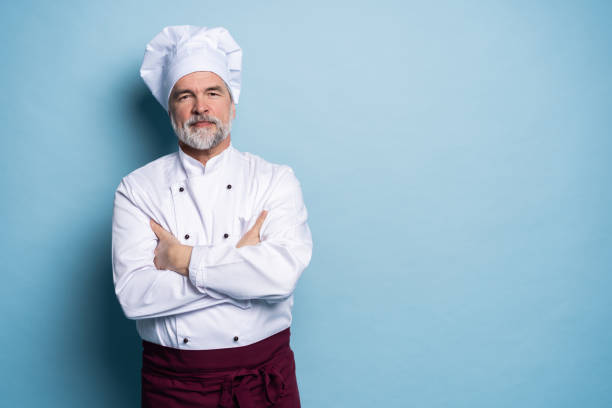 istock Attractive smiling cheerful chef isolated on blue. 1166728546