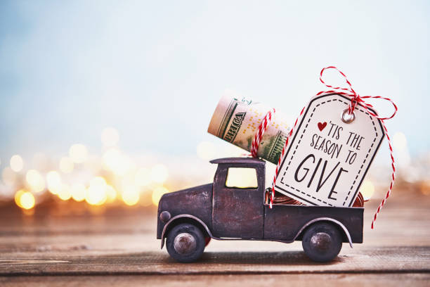 Season to Give. Truck carrying roll of dollars with holiday background Season to Give. Truck carrying roll of dollars with holiday background gift tag note photos stock pictures, royalty-free photos & images