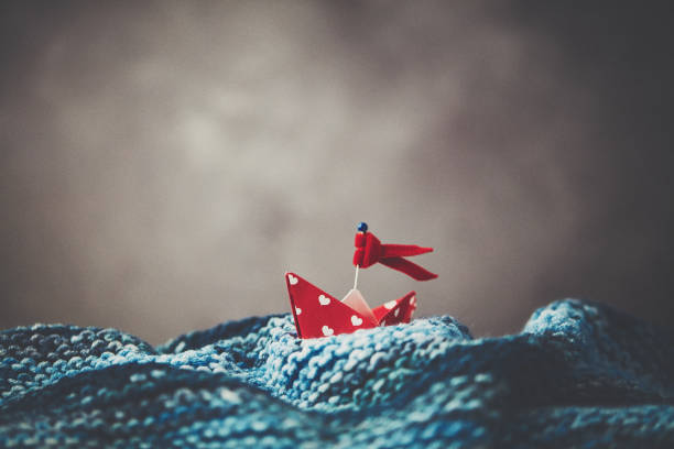 istock Handmade origami boat on handmade waves with stormy sky 1166730011