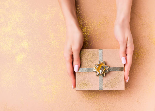 istock Celebration flat lay with gift box and female hand on gold 1166732034