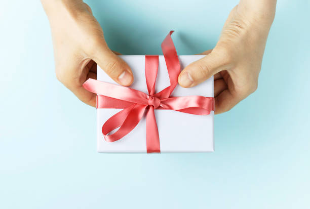 istock Male hands holding gift box with ribbon on blue background, top view 1166732080