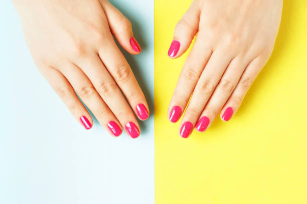 istock Female hands with pink manicure on yellow and blue background 1166732083