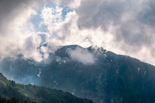 istock High rocky mountain peak in the clouds. 1166734052