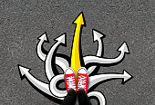 Feet and many arrows on road background. Pair of foot standing on concrete with color graffiti arrow sign