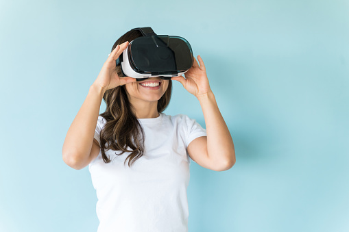 Smiling Caucasian woman using VR glasses on blue background